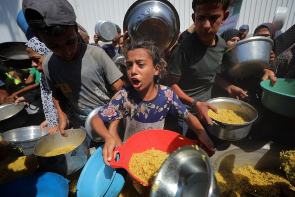 Displaced Gazans carry pots and pans for hot meals at the Nuseirat refugee camp in Gaza City amid an ongoing Israeli blockade and attacks against Hamas on Thursday. Photo by Hassan Al-Jadi/UPI