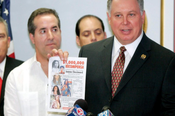 In 2005, Jorge Mas Santos, chairman of the board for the Cuban American Foundation, listens to Albio Sires, New Jersey state assembly speaker of the House, holds a reward pamphlet for Assata Shakur, who fled to Havana. Shakur was wanted for the shooting death of a New Jersey state trooper in 1979. File Photo by John Riley/EPA
