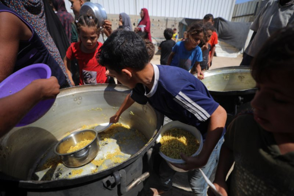 A Palestinian child scrapes an empty kettle to collect leftover food at a distribution site operated by a charity in the Nuseirat refugee camp in Gaza City. Australia, Britain and Canada issued statements Sunday formally recognizing a Palestinian state amid growing violence and famine as a result of the Palestinian-Israeli conflict. Photo by Hassan Al-Jadi/UPI