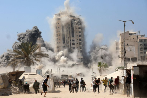 Palestinians flee as smoke billows from Mushtaha Tower, an apartment building in Gaza City on Friday, shortly after the Israeli Defense Forces announced they would target high-rises as part of their ongoing war against Hamas. Israel said the building was being used by Hamas. Photo by Omar Ishtiwi/UPI