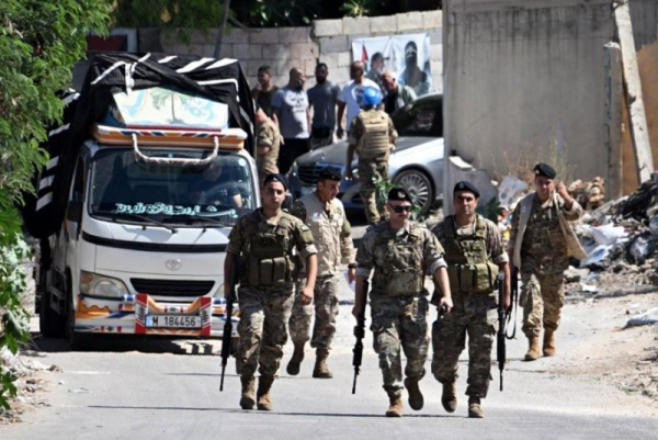 Lebanese Army soldiers walk next to a pickup truck carrying weapons at Beddawi Palestinian refugee camp, northern Lebanon, on September 13. The Army received the fourth batch of weapons surrendered by Palestinian refugee camps as part of a disarmament deal reached in May. Photo by Wael Hamzeh/EPA