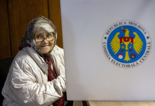 An elderly woman peeks out from a voting booth at a polling station, in Chisinau, Moldova, on Sunday, Sept. 28. Photo by Dumitru Doru/EPA