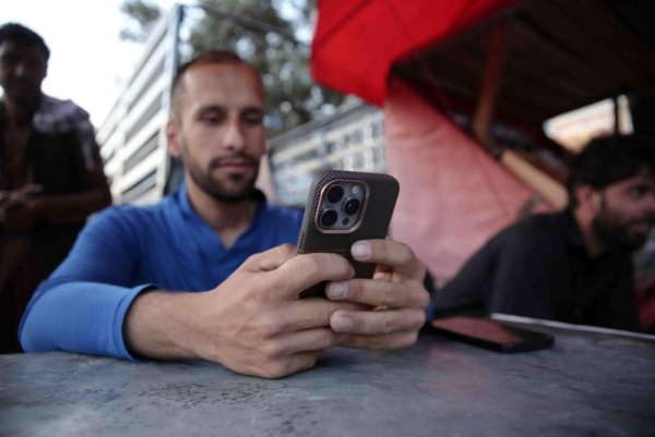 An Afghan man uses a mobile phone as internet and telecom services are gradually restored after almost three days of closures in Kabul Wednesday. Photo by Samiullah Popal/EPA