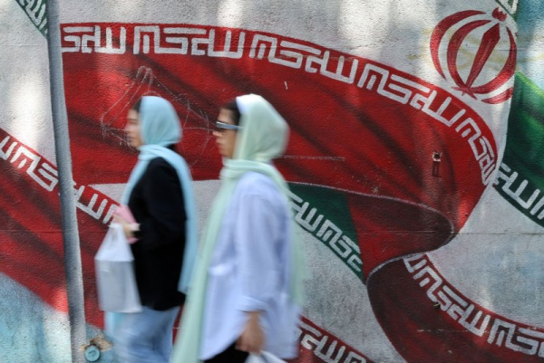 Iranians walk past next to a wall painting of Iran's national flag on a street in Tehran, Iran, Iran said a man accused of spying for Israel was executed Monday, among nine executed for espionage since June when the Jewish state attacked the Arab nation. File photo by Abedin Taherkenareh/EPA